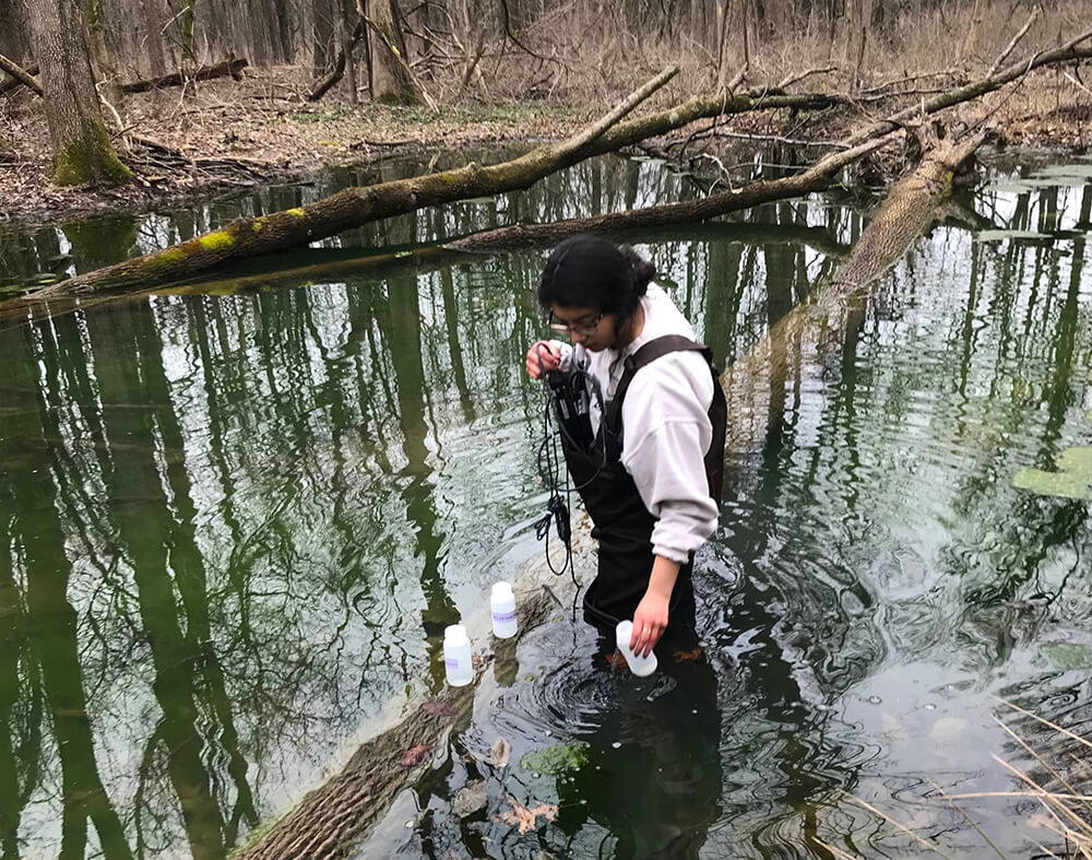 Student taking water samples from stream