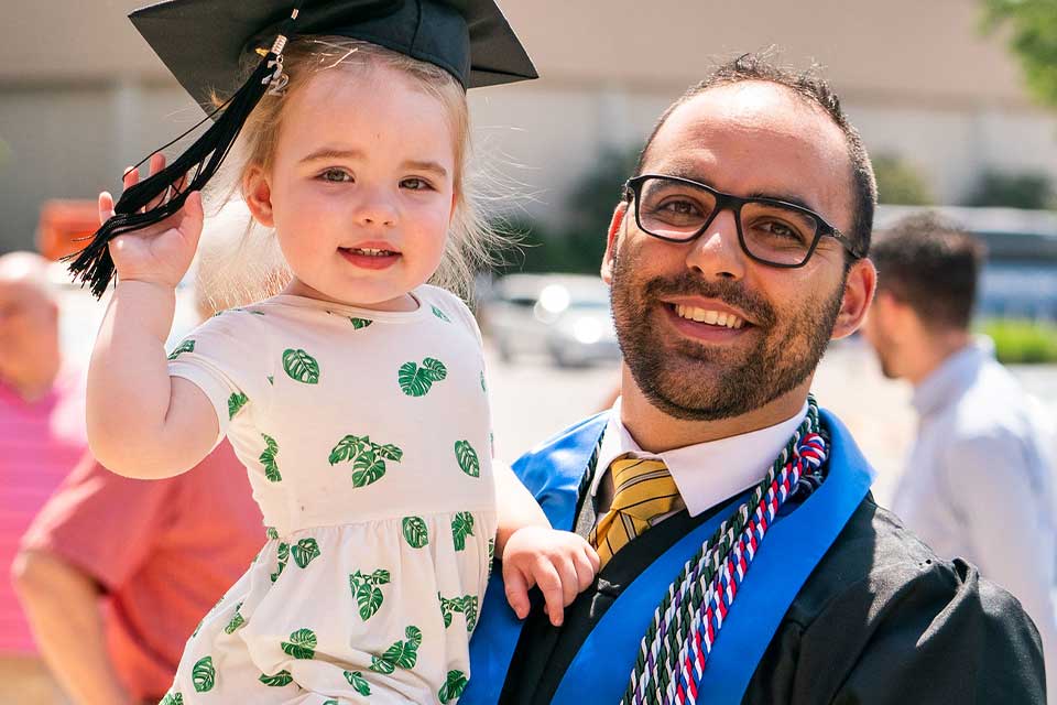 A Bellarmine graduate celebrates while holding his daughter