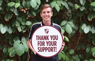 Alumni representative holds up a thank you poster