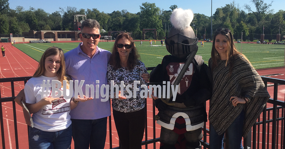 Parents and family hold up a Bellarmine sign by the athletic track