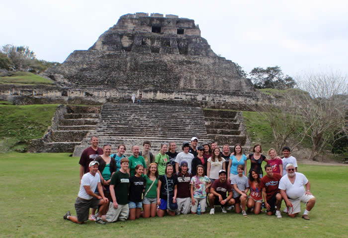 students gather for a group photo in front of an ancient structure