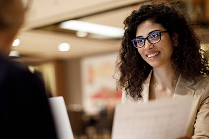 someone hands an analytics report across the table in a meeting