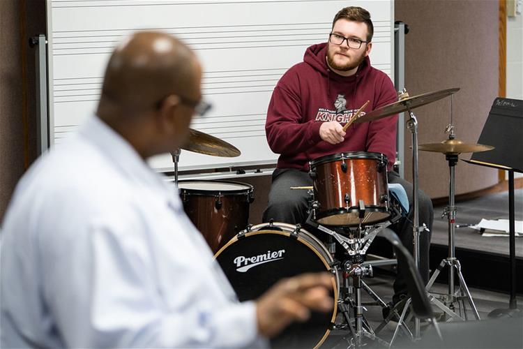 A Bellarmine University Music student plays the drums while receiving instruction from a professor.