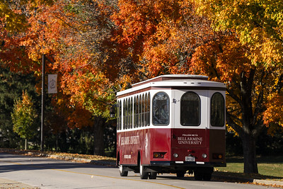 The Bellarmine trolley is parked under colorful trees in the fall