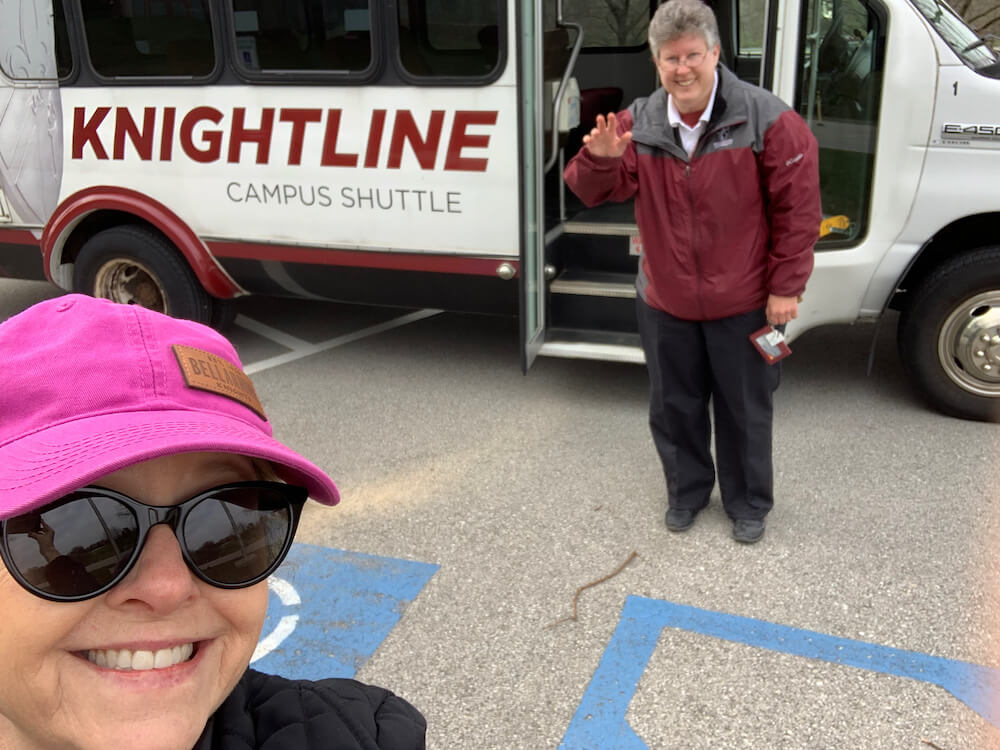two people standing beside the campus shuttle