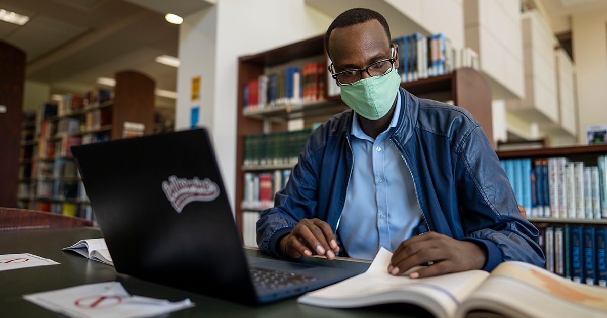 Student in Bellarmine's Library with a laptop and a book