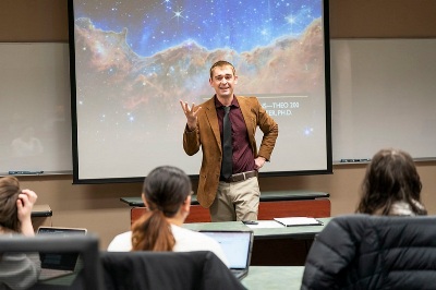 a smarmy professor presents a lecture to his theology class