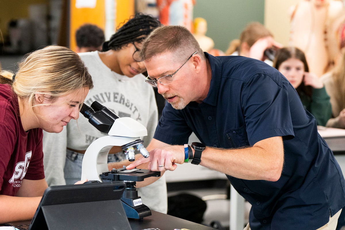 instructor and student look through a microscope