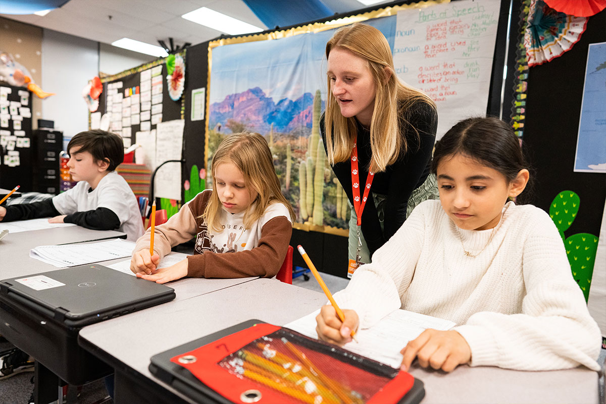 teacher oversees young students practicing math