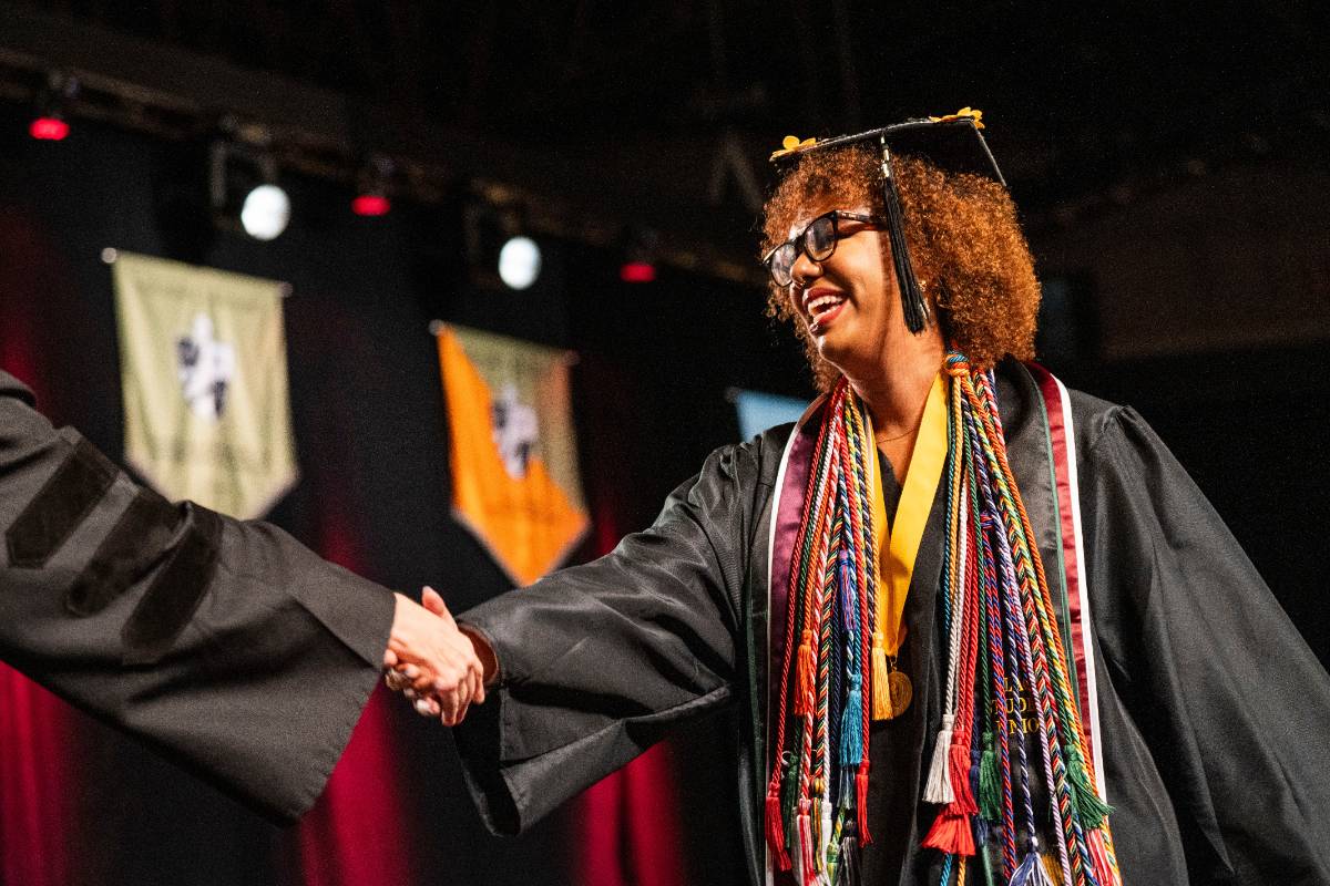 Graduate shakes hands with the presenter at commencement
