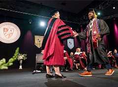 Dr Donovan hands a student a diploma during graduation