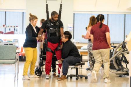 Clinic workers help a patient with an exercise.
