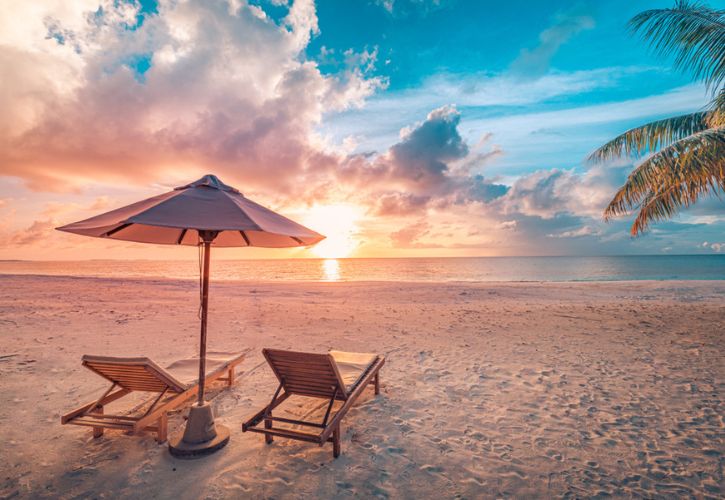 Beach chairs and umbrella at sunset