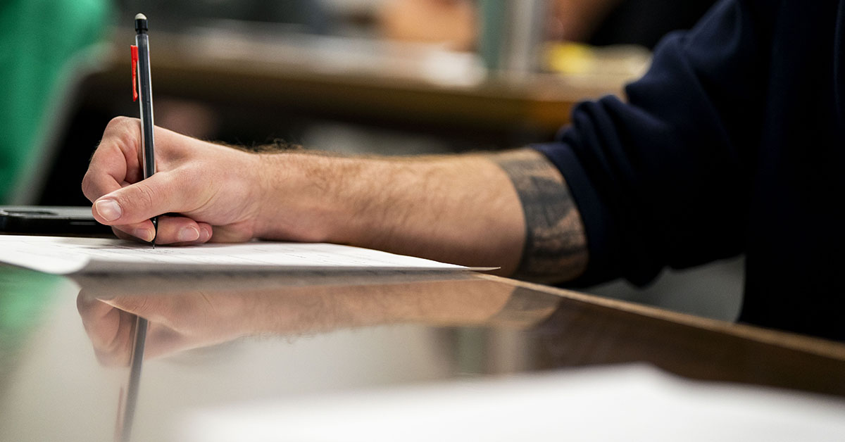 A man's hand holding a pen and writing. 