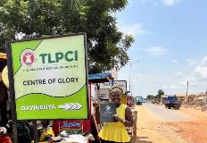 esther awovi akafia poses for a photo next to a sign on a dirt road in Ghana