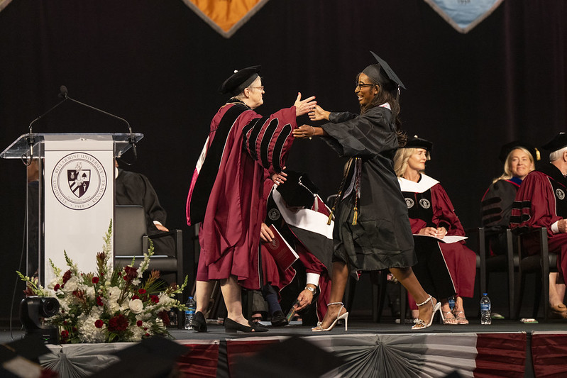 Dr. Donovan embraces a student on stage at the 2025 commencement